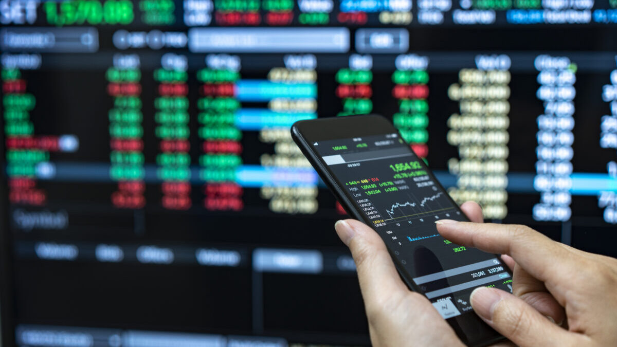 Businessman checking stock market data. He using a mobile phone. Analysis economy data on forex earn graph.